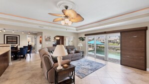 A spacious living area with a ceiling fan, a dining area with a table and chairs, and a view of an outdoor pool through large sliding glass doors. - Family-friendly Waterfront 4br Pool Punta Gorda Isles 4 Bedroom Home (Punta Gorda)