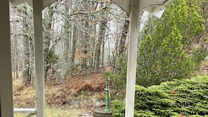 Un belvédère en bois offrant une vue sur une zone boisée et un jardin bien entretenu.