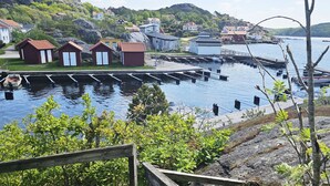 Un port avec des bateaux, une jetée en bois et de petits bâtiments aux toits rouges.