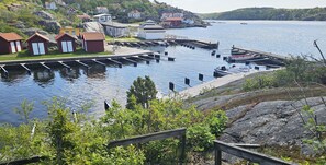 Un muelle a orillas del lago con botes, un embarcadero de madera y casas a lo largo de la costa.