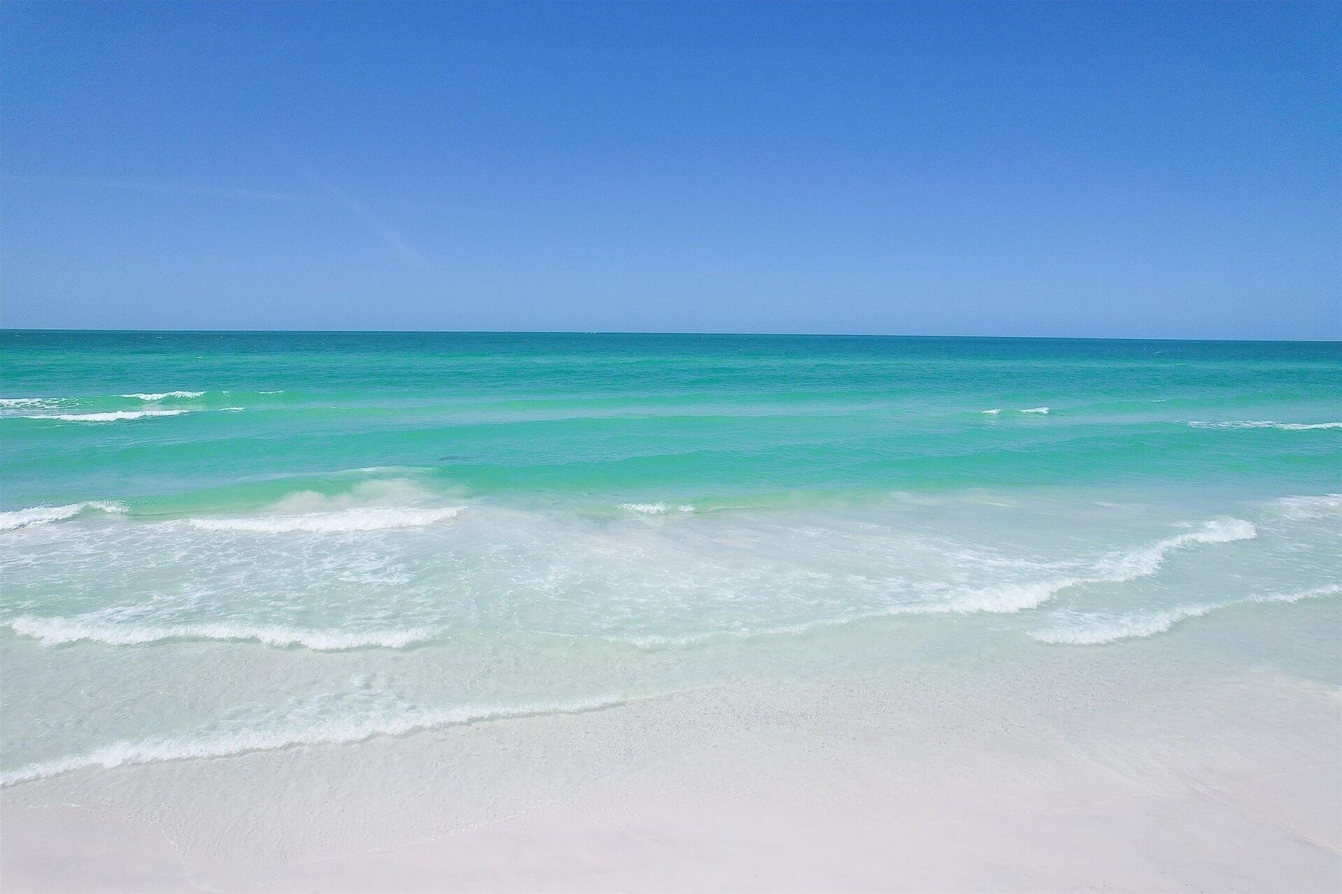 Une plage à l’eau turquoise et au sable blanc.