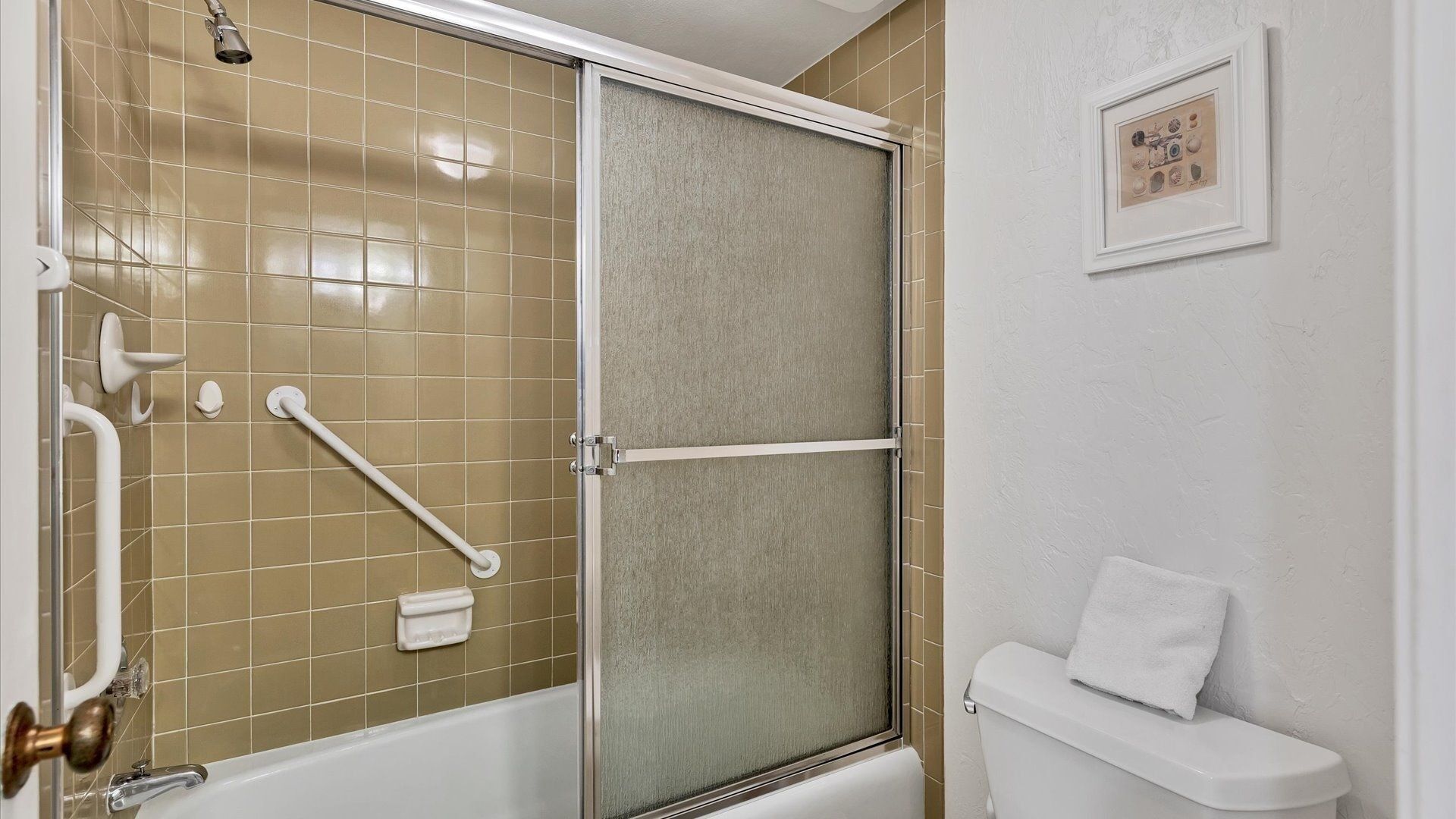 Un baño con cabina de ducha, inodoro y barra de apoyo.