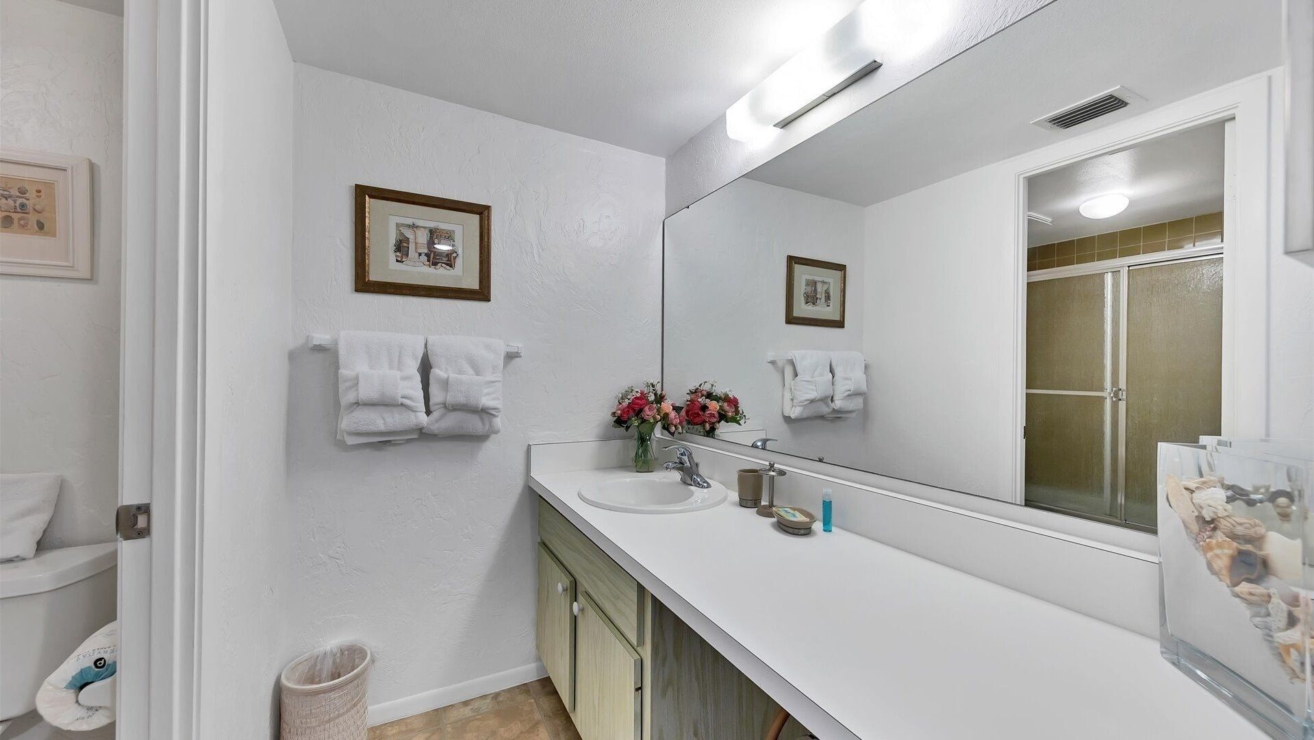 A bathroom with a white sink, a mirror, and two towels hanging on the wall.