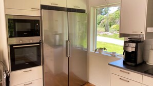 A modern kitchen with a stainless steel refrigerator, oven, and coffee maker. - Villa with sauna, 650 m to the beach | SE09135 (Varekil)