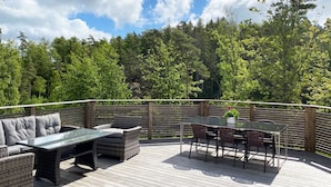A deck with outdoor furniture, including a sofa, chairs, and a table. - Villa with sauna, 650 m to the beach | SE09135 (Varekil)
