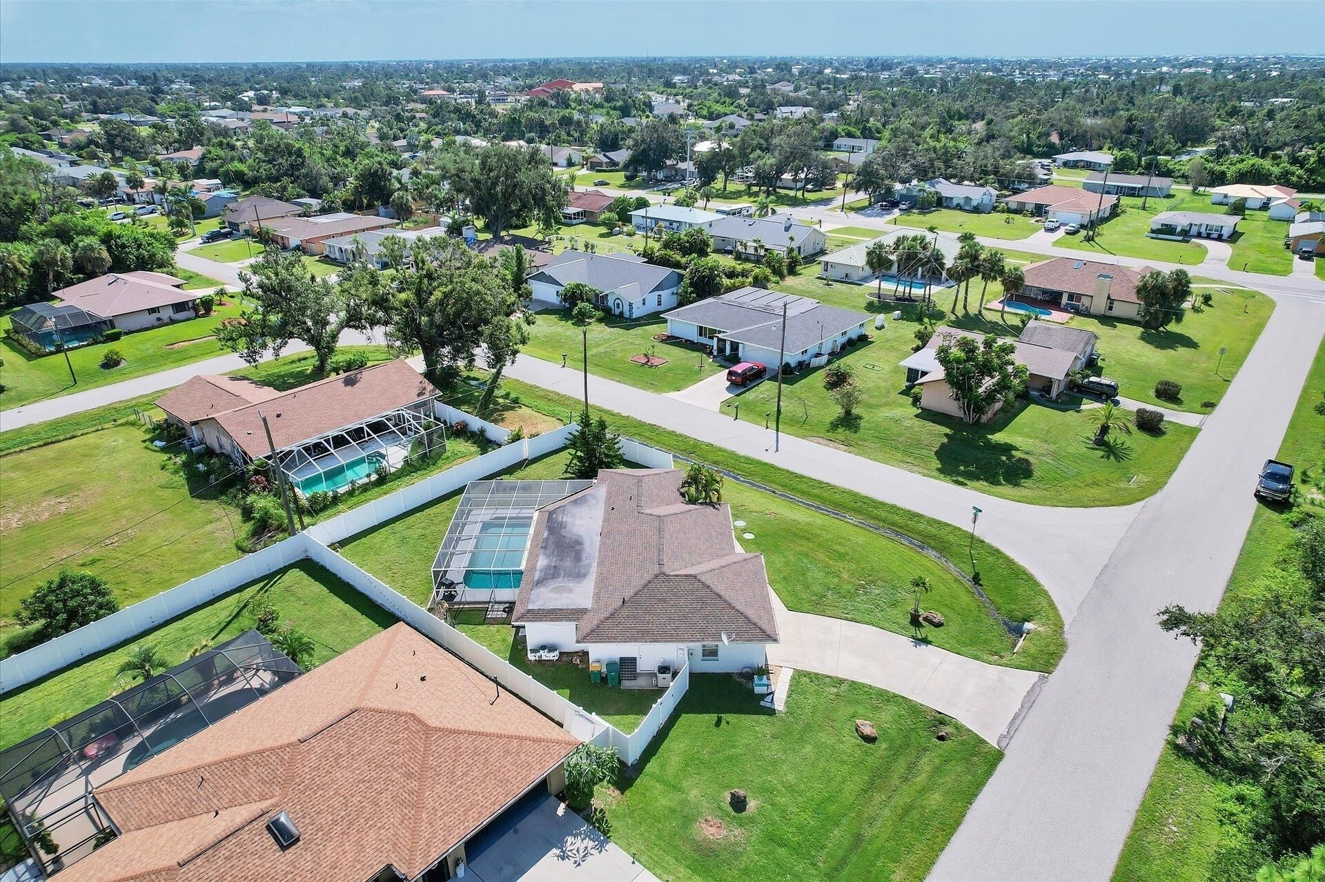 Vista aerea di una zona residenziale con case, prati verdi e una piscina.