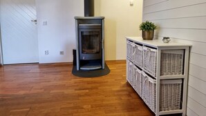 A room with a wood-burning stove, wicker baskets, and a white door. - Lovely apartment, perfect for exploring Tjörn and Orust | SE09153 (Varekil)