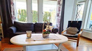 A living room with a sofa, a chair, a coffee table, and a window with curtains. - Lovely apartment, perfect for exploring Tjörn and Orust | SE09153 (Varekil)