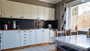A modern kitchen with white cabinets, a wooden countertop, and a dining table with chairs. - Lovely apartment, perfect for exploring Tjörn and Orust | SE09153 (Varekil)