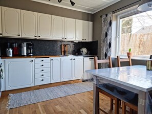 A modern kitchen with white cabinets, a wooden countertop, and a dining table with chairs. - Lovely apartment, perfect for exploring Tjörn and Orust | SE09153 (Varekil)
