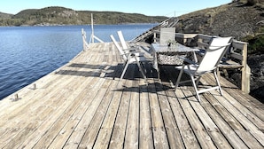 Un muelle de madera con una mesa y sillas que da a un lago tranquilo.