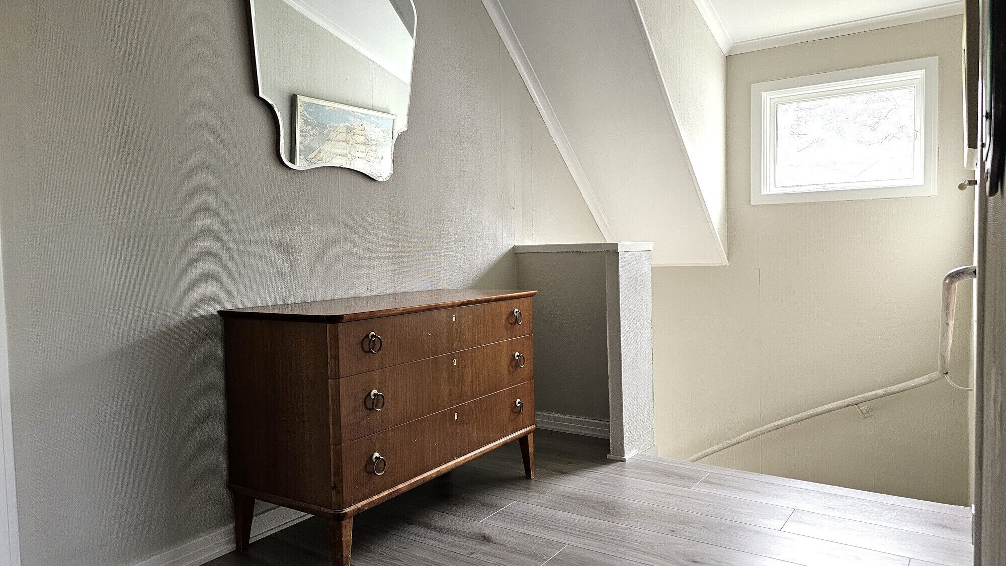 Ein Zimmer mit einem Holzschrank, einem Spiegel und einer Tür mit einem Fenster.