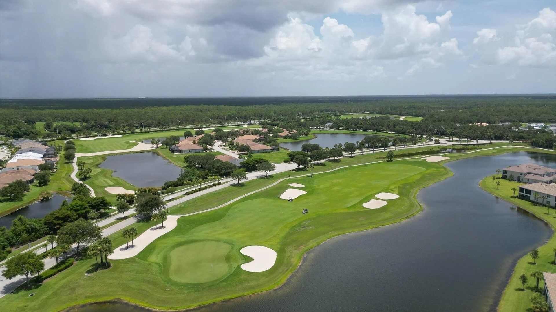 A golf course with multiple ponds, surrounded by residential buildings and lush greenery.