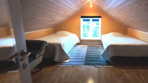 A small attic room with two single beds, a wooden floor, and a window at the far end. - Stay central & close to the sea in Henån | SE09155 (Henån)
