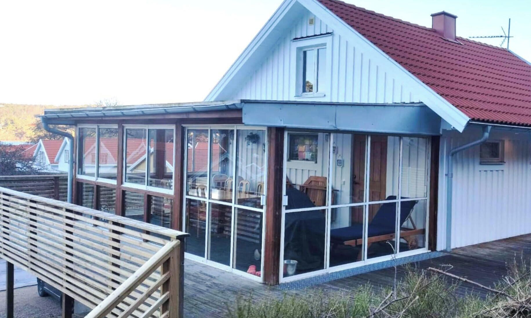 Ett hus med ett glashus, en träterrass och ett rött tak.