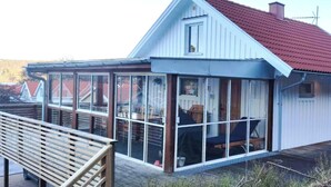 A house with a glass conservatory, a wooden deck, and a red roof. - Stay central & close to the sea in Henån | SE09155 (Henån)