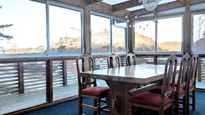 A wooden dining table with six chairs, large windows, and a view of a hilly landscape. - Stay central & close to the sea in Henån | SE09155 (Henån)