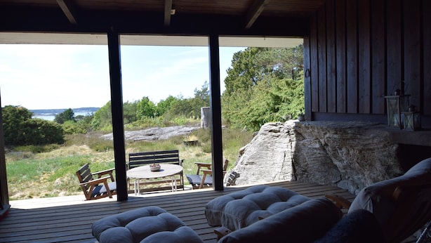 Un patio in legno con posti a sedere all'aperto, un camino in pietra e vista sul paesaggio circostante.