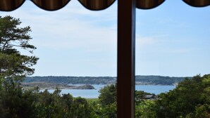 Vista dalla finestra su un lago, circondato da alberi e una costa in lontananza.