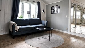 A modern living room with a blue sofa, a round coffee table, and a large window with curtains. - Charming House near Lysekil & Skaftö | SE09160 (Uddevalla)