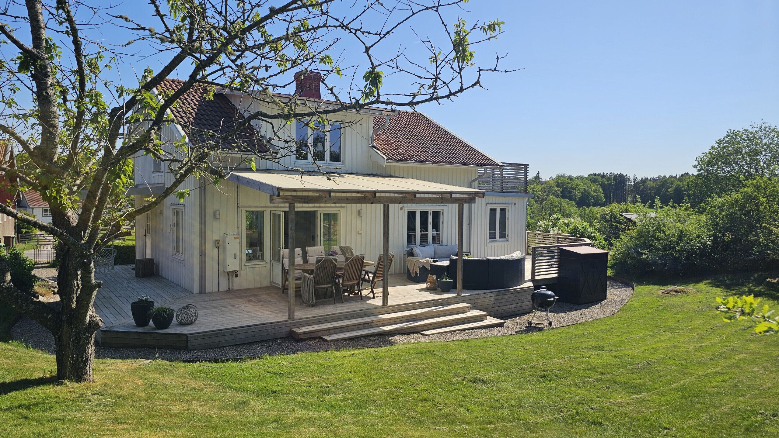 A two-story house with a patio, outdoor seating, and a barbecue area.