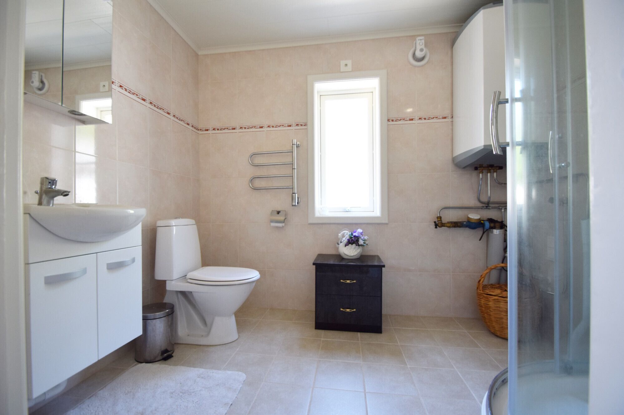 A bathroom with a toilet, sink, and a small cabinet.