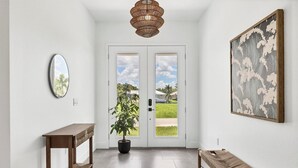 A hallway with a wooden bench, a potted plant, a mirror, and a framed artwork. - Punta Gorda 3-Bedroom Canalfront Vacation Home with Pool 3 Home (Punta Gorda)