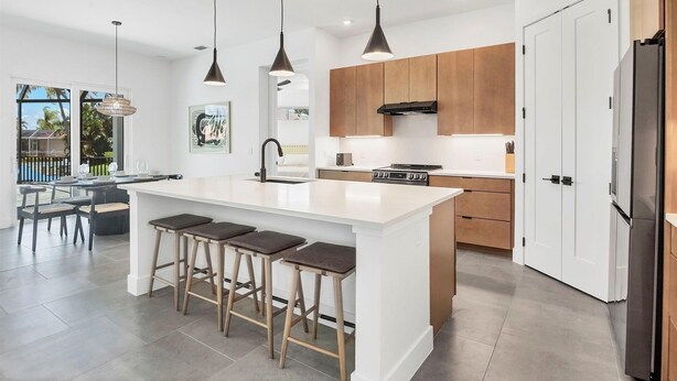 A modern kitchen with a central island, wooden cabinets, and pendant lighting. - Punta Gorda 3-Bedroom Canalfront Vacation Home with Pool 3 Home (Punta Gorda)