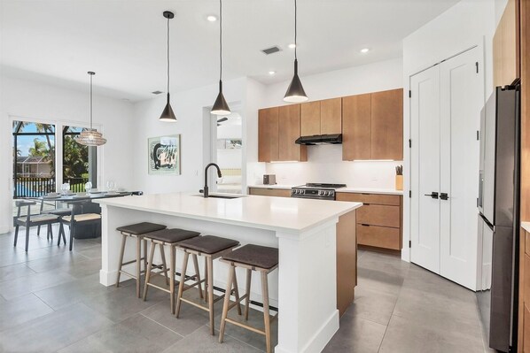 A modern kitchen with a central island, wooden cabinets, and pendant lighting. - Punta Gorda 3-Bedroom Canalfront Vacation Home with Pool 3 Home (Punta Gorda)