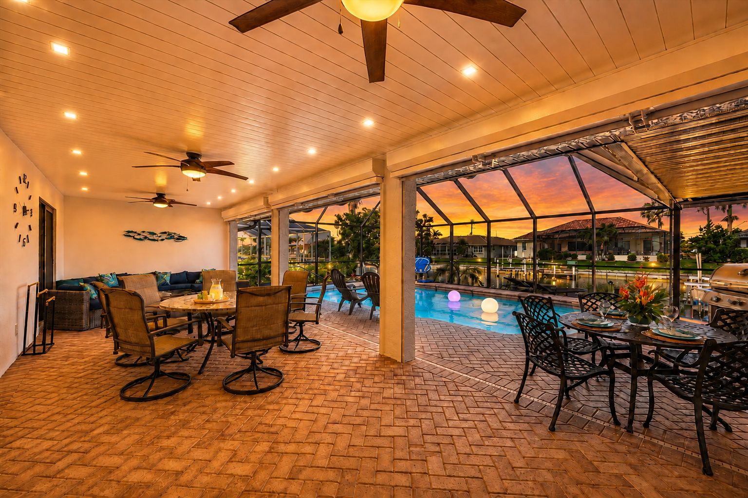 An indoor patio area with a pool, seating, and a sunset view.