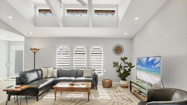A modern living room with a leather sofa, a wooden coffee table, and a large TV. - Punta Gorda Isles 3-Bedroom Canal-front Pool Home with Dock 3 Home (Punta Gorda)