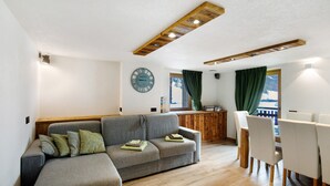 A living room with a sofa, chairs, a wooden ceiling, a clock, and a window with curtains. - Apartment 'Monte Vago' with Mountain View, Balcony and Wi-Fi (Livigno)