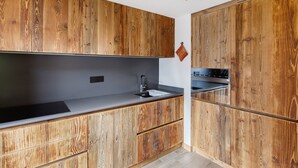 A kitchen with wooden cabinetry, a black countertop, and a stainless steel sink. - Apartment 'Monte Vago' with Mountain View, Balcony and Wi-Fi (Livigno)