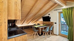 Una cocina moderna con techo de madera, un área de comedor con mesa y sillas, y vistas a través de un vidrio.