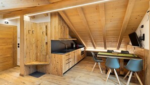 Cocina compacta con armarios de madera, estufa integrada y comedor con mesa y sillas.