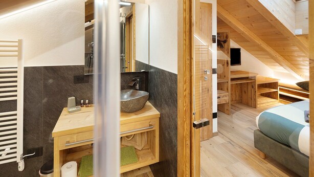 Un baño moderno con tocador de madera, un espejo grande y un lavabo empotrado.