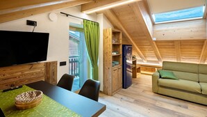 Una habitación estilo loft con comedor, sofá, televisor y techo de madera.