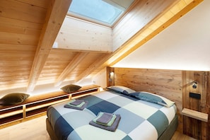 A bedroom with a skylight, wooden beams, a bed with pillows, and a bedside table. - Mansarda Rin Da Gen Apartment with Mountain View, Balcony and Wi-Fi (Livigno)