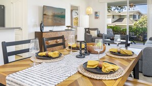 A dining area with a wooden table set for four, featuring woven placemats, black plates, and yellow napkins.