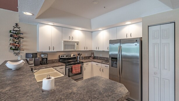 A modern kitchen with white cabinets, stainless steel appliances, a built-in microwave, a double oven, and a refrigerator. - Relaxing Townhome By Lemon Bay, Minutes To Beach 2 Bedroom Townhouse (Englewood)