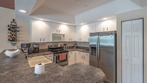 Eine moderne Küche mit weißen Schränken, Edelstahlgeräten, einer eingebauten Mikrowelle, einem Kombi-Backofen und einem Kühlschrank.