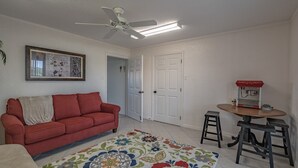 A living room with a red sofa, a ceiling fan, a framed picture, and a coffee machine. - Relaxing Townhome By Lemon Bay, Minutes To Beach 2 Bedroom Townhouse (Englewood)