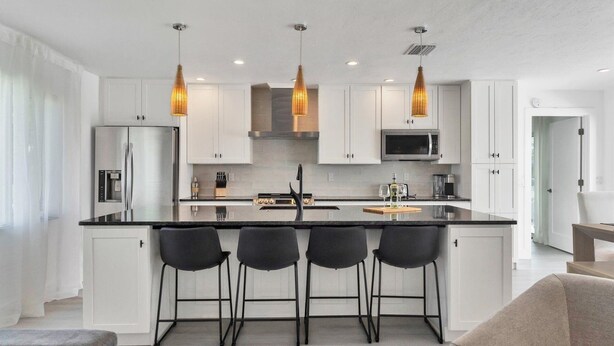 A modern kitchen with white cabinets, a central island with bar stools, stainless steel appliances, and pendant lighting. - Bird Section Punta Gorda Isles, Dog Friendly, Canal, Kayaks 3 Bedroom Home (Punta Gorda)