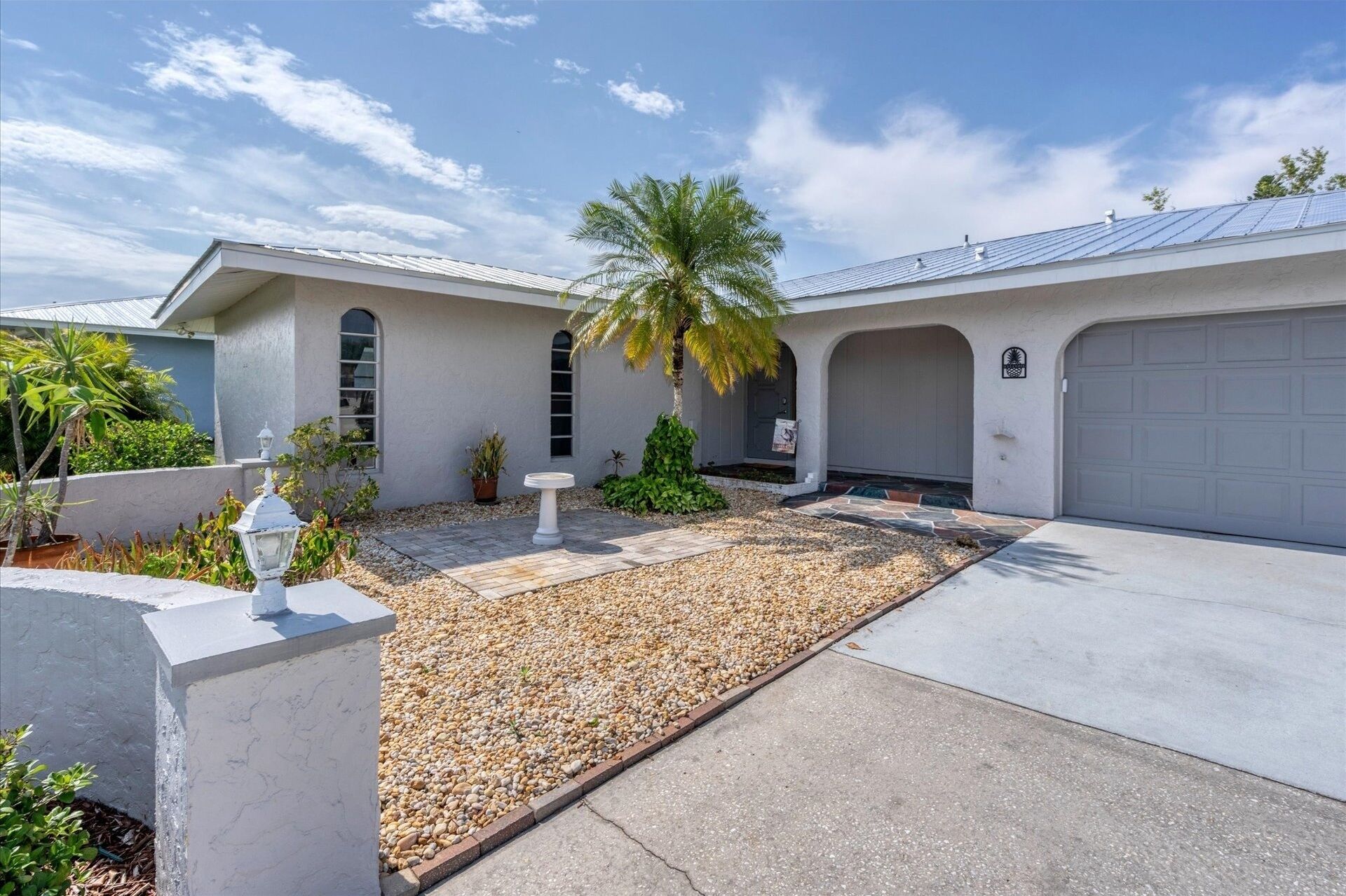 A modern house with a garage, a palm tree, and a well-maintained garden.