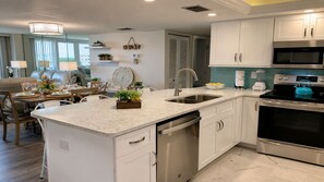 A modern kitchen with white cabinetry, a stainless steel sink, and a built-in oven. - Anchorage Resort 2 Bedroom Condo 6th Flr, Beach Access, Pool 2 Condo (Siesta Key)