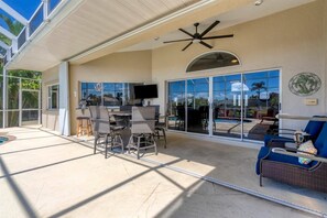 A covered patio area with a ceiling fan, outdoor seating, and a view of a swimming pool. - Punta Gorda Isles 3-Bedroom Private Pool Home on Canal with Dock 3 Home (Punta Gorda)
