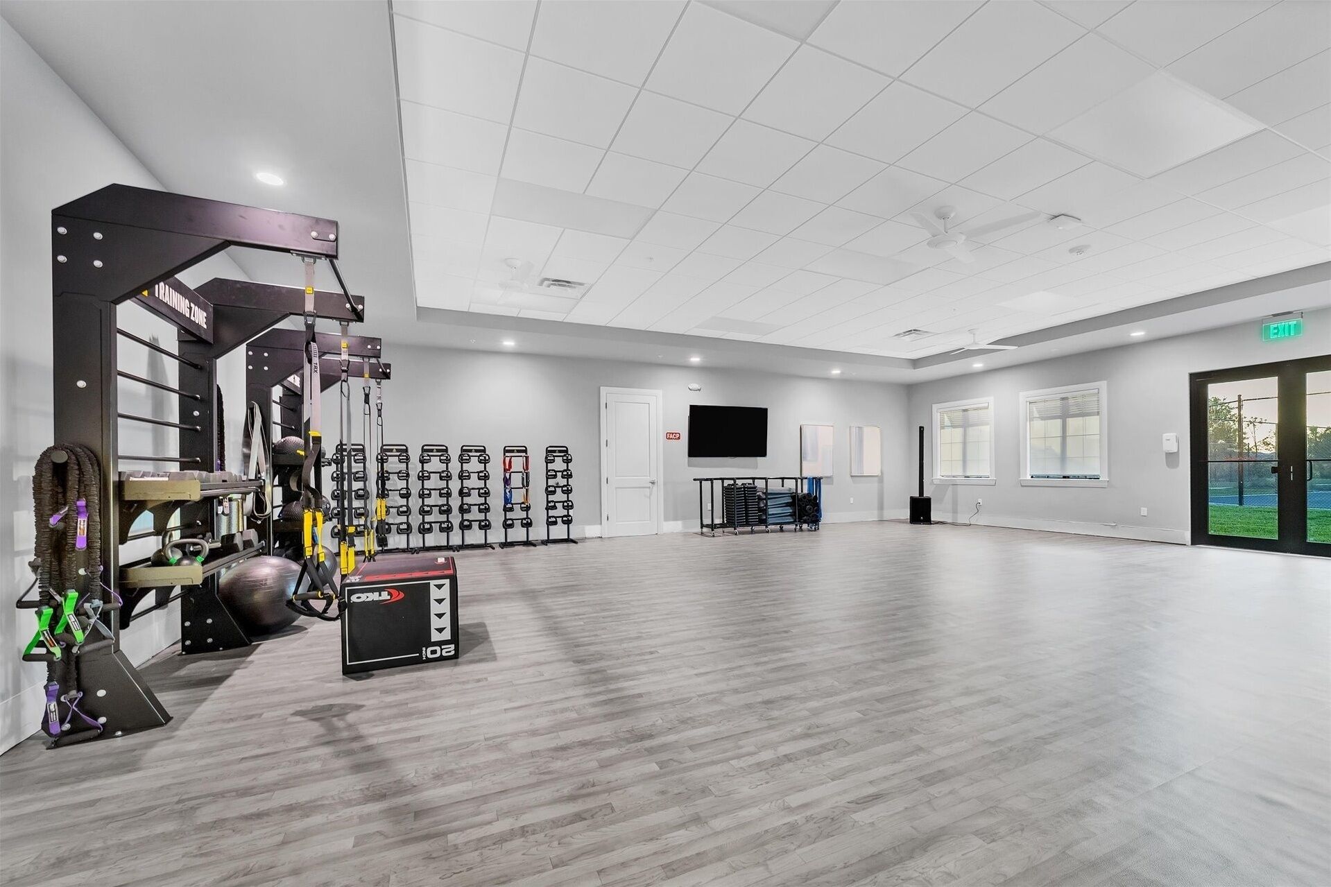 Une salle de sport spacieuse, équipée de divers appareils d’exercice, d’un téléviseur et d’une grande fenêtre.