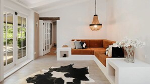 Un salon moderne avec un canapé blanc, un luminaire suspendu et un tapis en peau de vache.