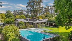 Une propriété résidentielle dotée d’une piscine, d’un patio couvert et d’un jardin bien entretenu.