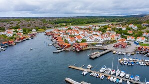 Un village côtier avec des maisons le long de la côte, un quai où sont amarrés des bateaux et une église.